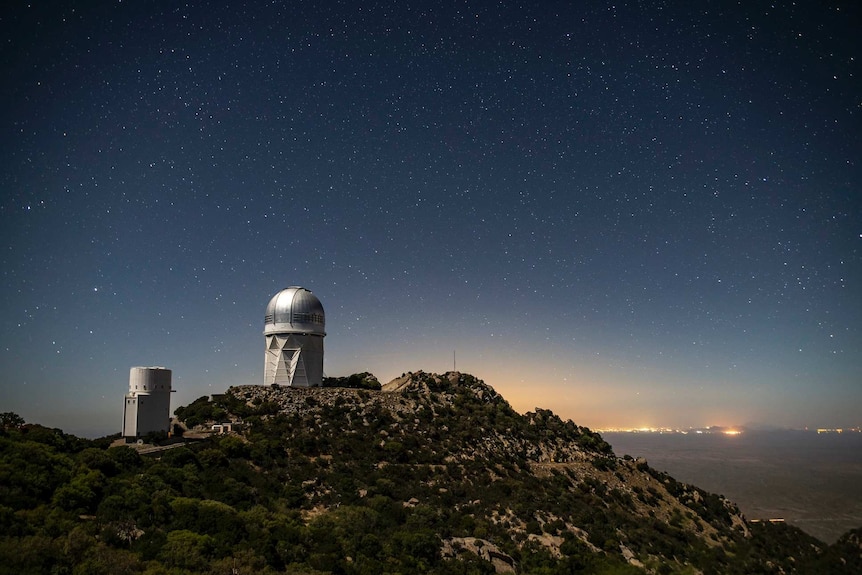 An Observatory and the sky with a city in the background.