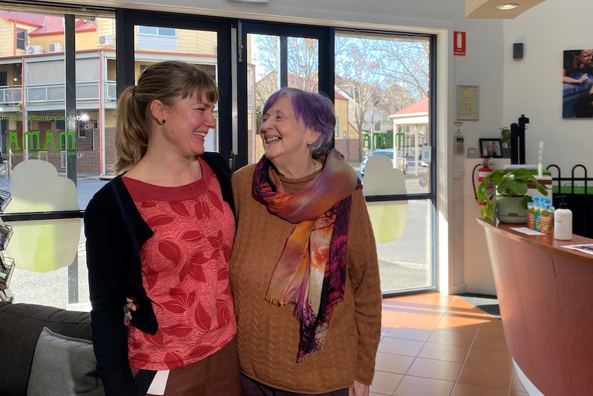 Two laughing women with their arms around each other.