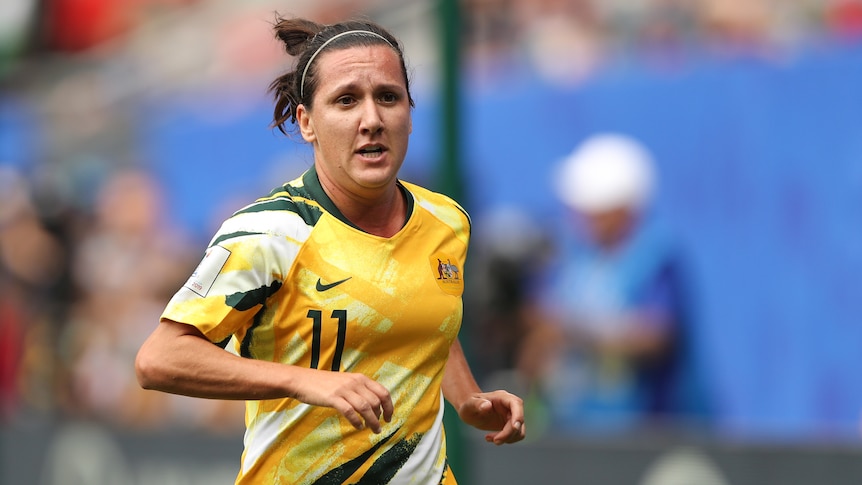 Lisa de Vanna runs wearing a yellow matildas jersey