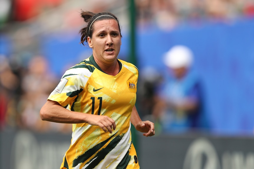 Lisa de Vanna runs wearing a yellow matildas jersey