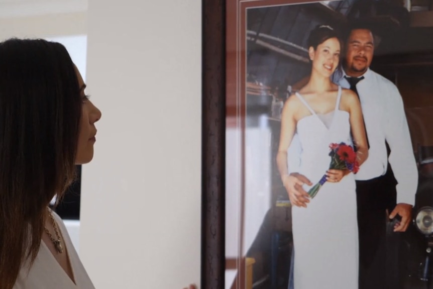 Grieving woman looks at her wedding photo framed on the wall