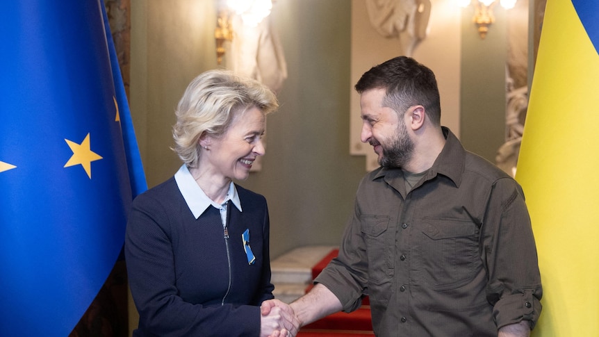 Zelenskyy shakes hands with Ursula von der Leyen in front of EU and Ukraine flags