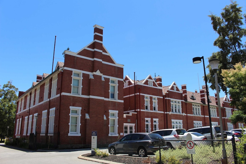 A wide shot of the brick and tile Perth Modern School in Subiaco with cars parked in front.