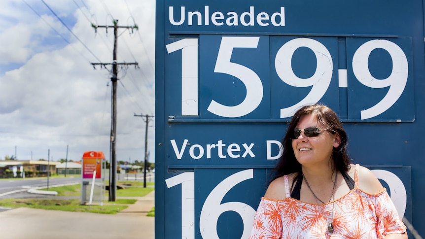 Woman standing in front of a petrol price sign.