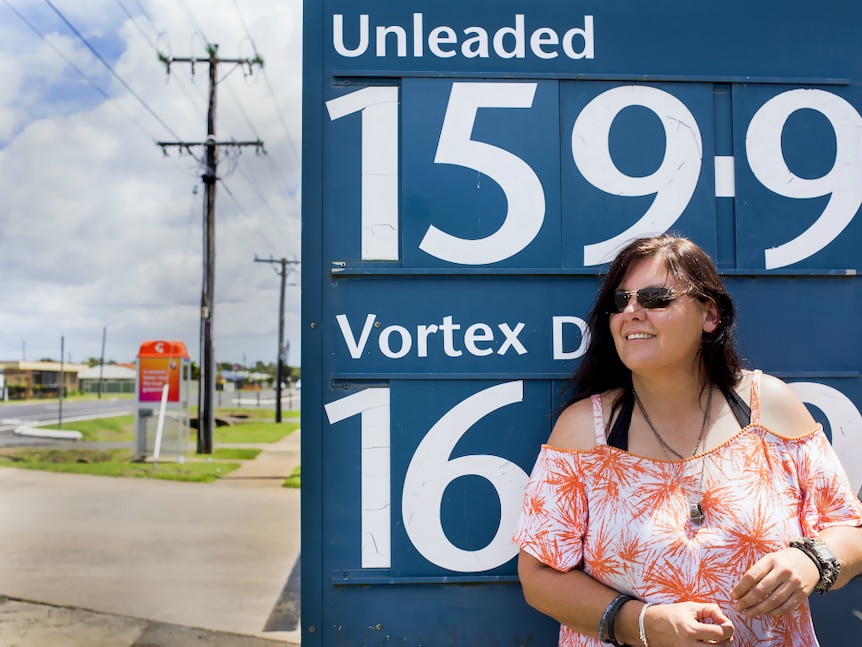 Woman standing in front of a petrol price sign.