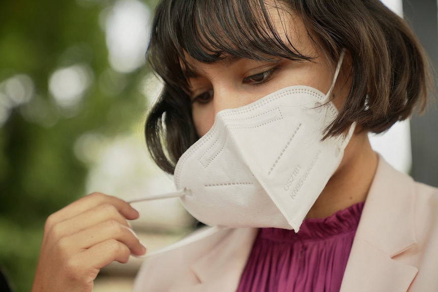 A woman removes her mask.