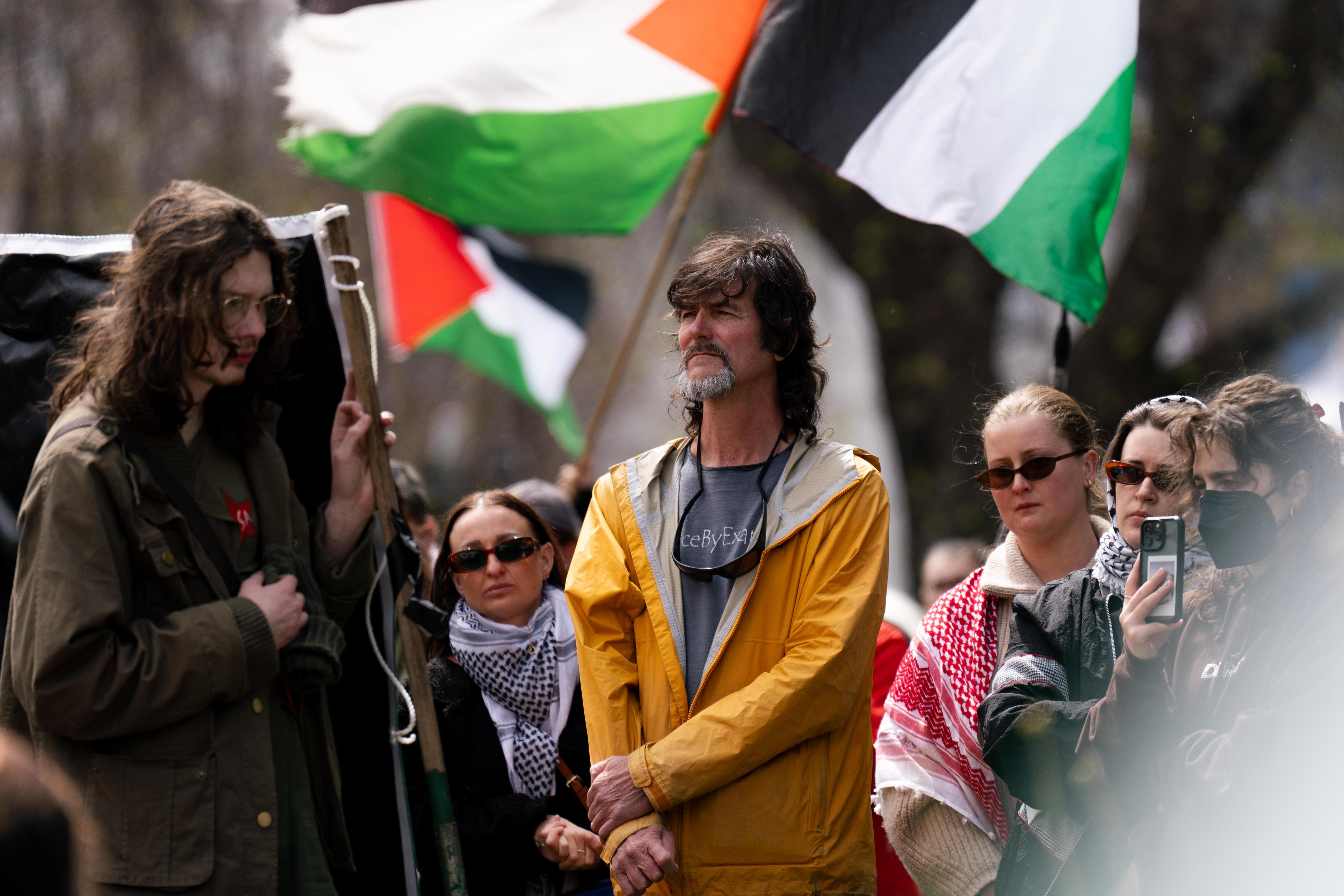 Man in yellow rain jacket with Palestinian flags behind him
