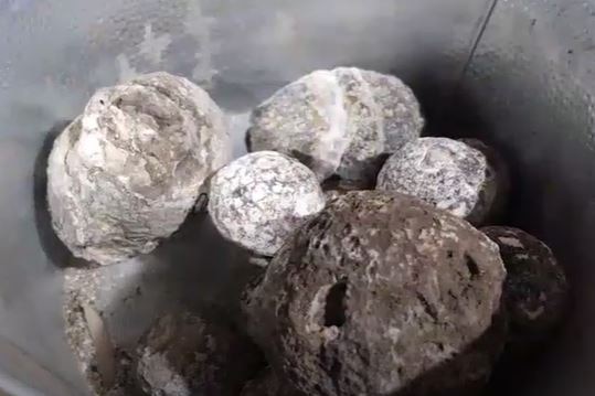 a pile of gray round stones in a bucket