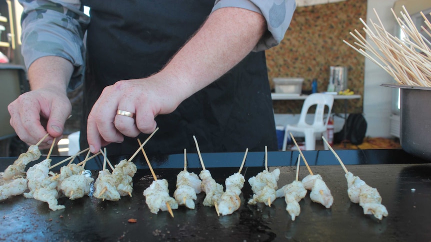 Close up photograph of defence force recruit's hands flipping skewers on bbq.