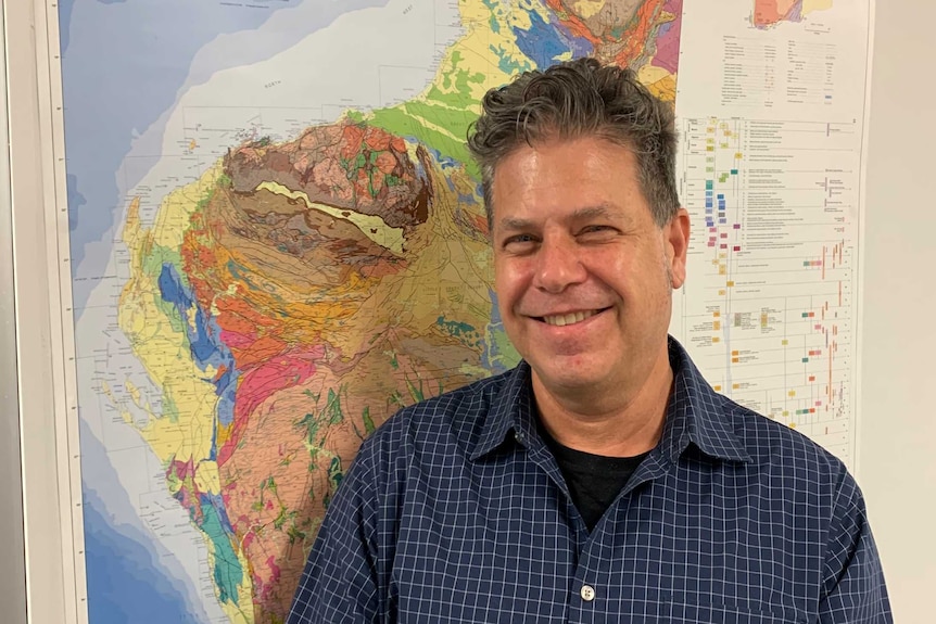 A man standing in front of a geological map of Western Australia.