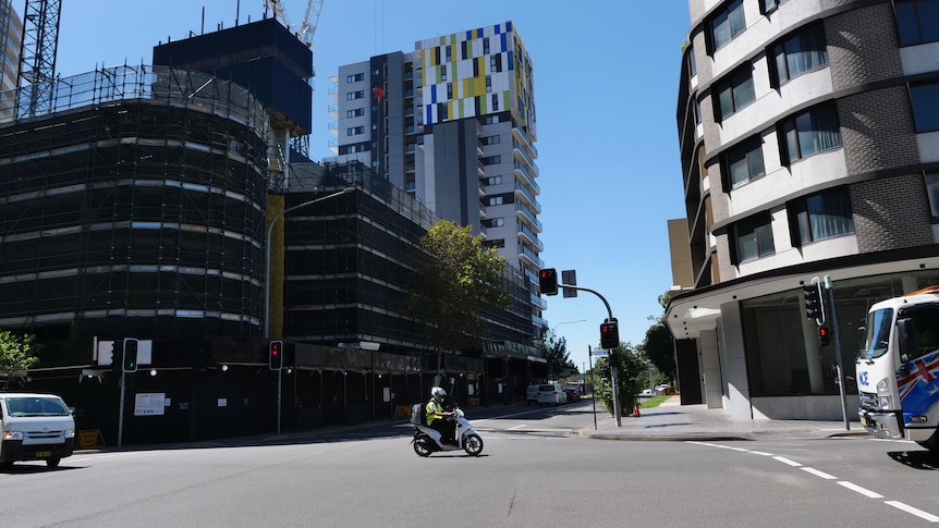An intersection with a multi-storey apartment building under construction on the left. 