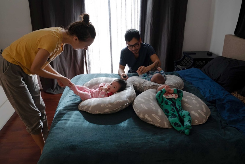 Samara and Uram handle the babies on the bed