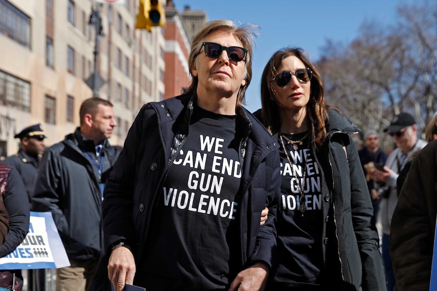 Paul McCartney and a woman are seen in a rally wearing 'we can end gun violence' tshitrts.