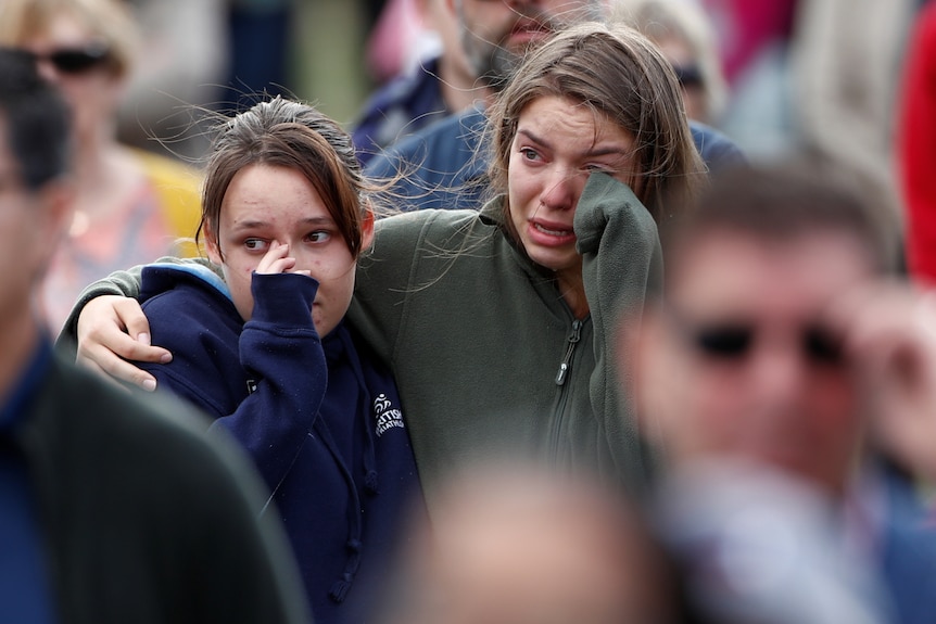 Two women cry as they watch on at a remembrance service in Christchurch
