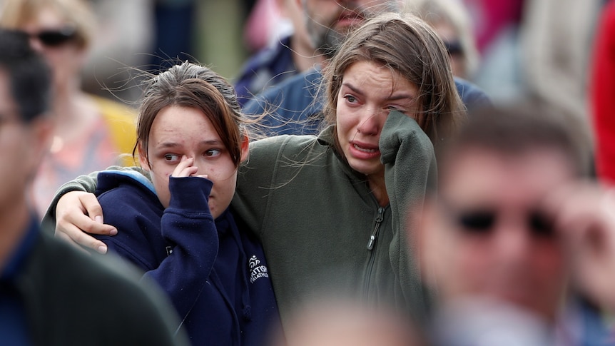 Two women cry as they watch on at a remembrance service in Christchurch