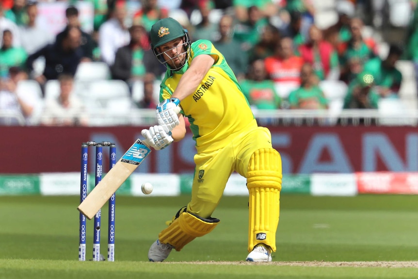 Aaron Finch leans back and swings at the ball with his bat, looking down at the ball