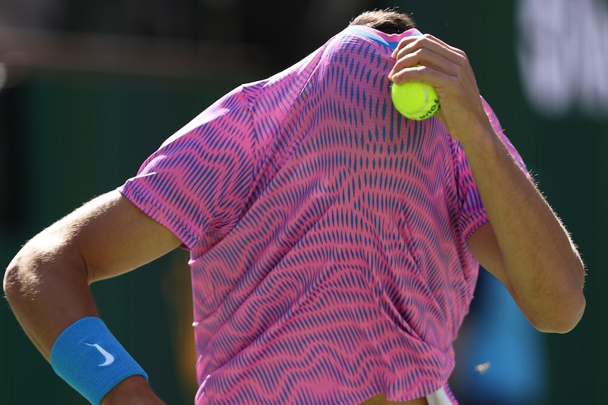 Carlos Alcaraz hides his face from a swarm of bees at Indian Wells Masters 1000. 