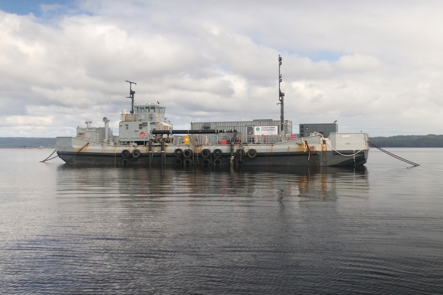 Barcaza anclada con un gran contenedor de envío se asienta sobre aguas grises