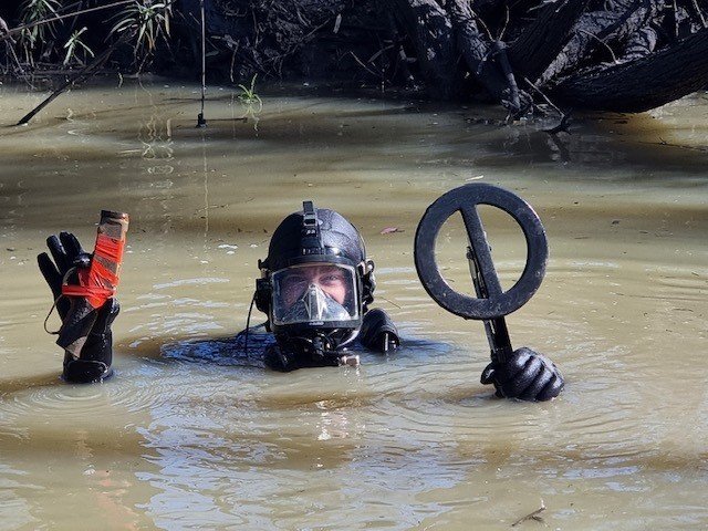 a police diver holds up a gun found in the river