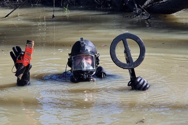 a police diver holds up a gun found in the river