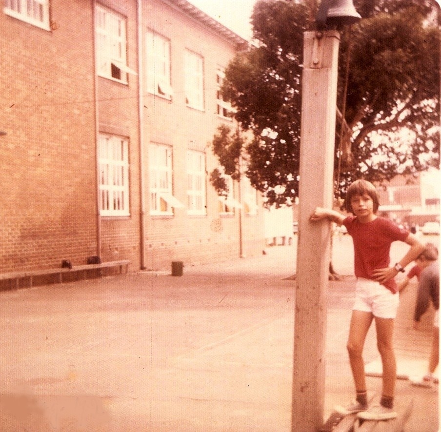 A boy leans against a telephone pole.