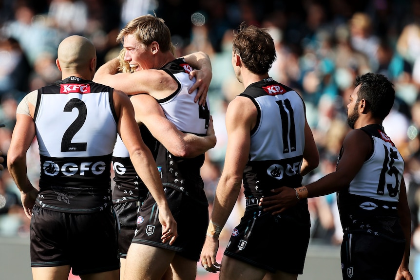 Five Port Adelaide AFL players celebrate a goal against Hawthorn.