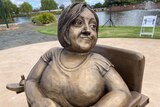 bronze statue of a woman sitting in a wheelchair.