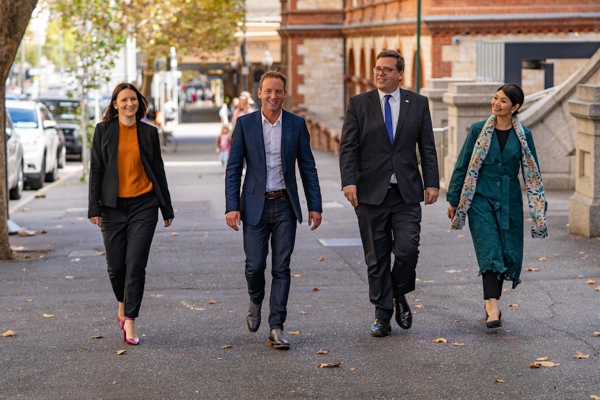 Two men and two women walk on a wide footpath