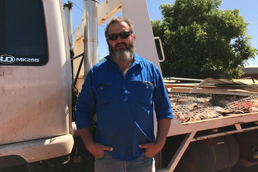 Malcolm Wall stands in front of an open-backed truck filled with building waste.