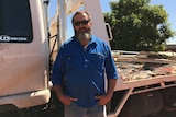 Malcolm Wall stands in front of an open-backed truck filled with building waste.