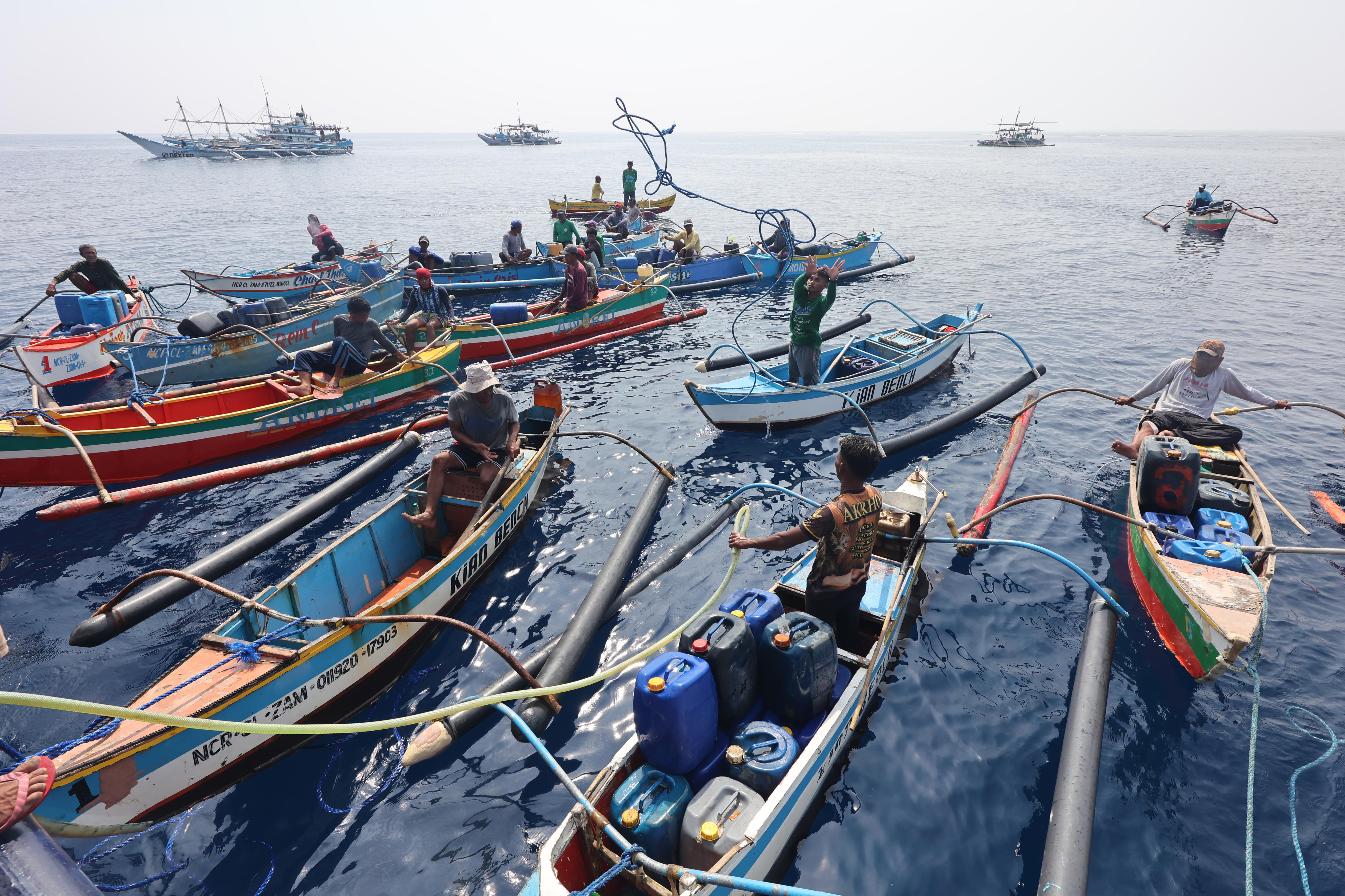 Filipino fishermen dock their boats beside a government supply ship distributing oil and food
