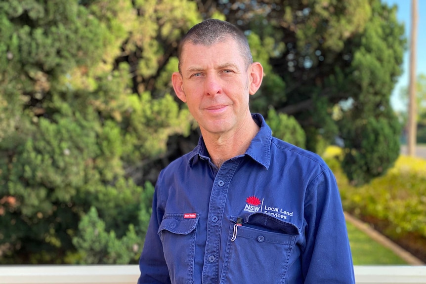 A man stands in a blue shirt.