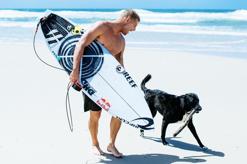 Mick Fanning pets his dog on the beach