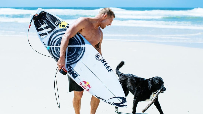 Mick Fanning pets his dog on the beach
