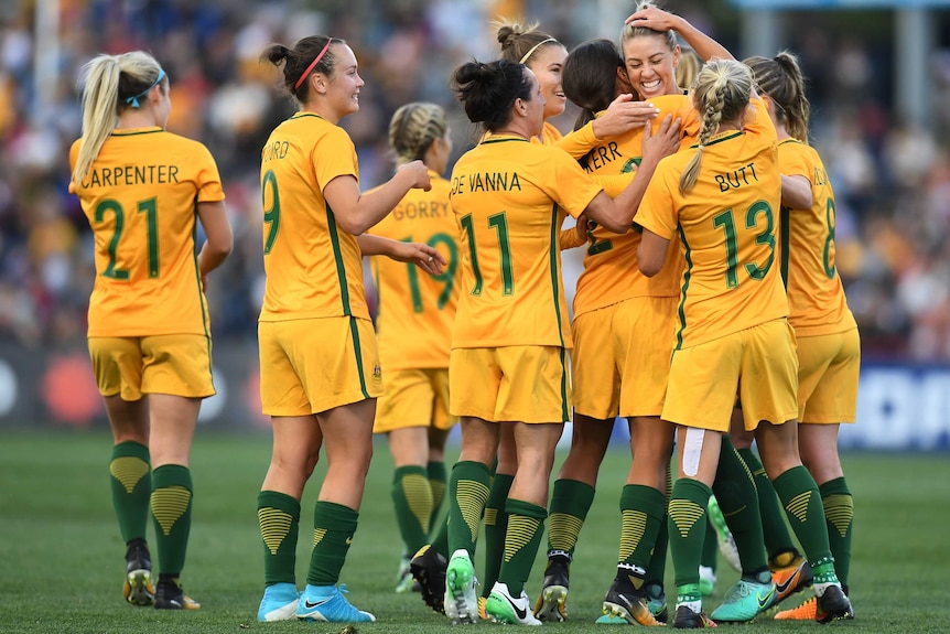 The Matildas hug each other as they celebrate a goal against Brazil.