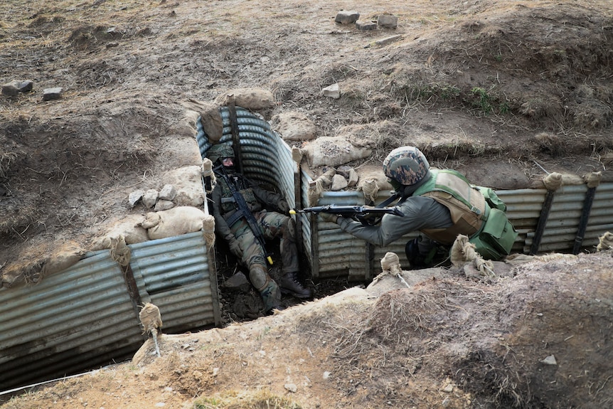 Ukrainian soldiers lay in trenches as part of a military exercise at a military training camp.
