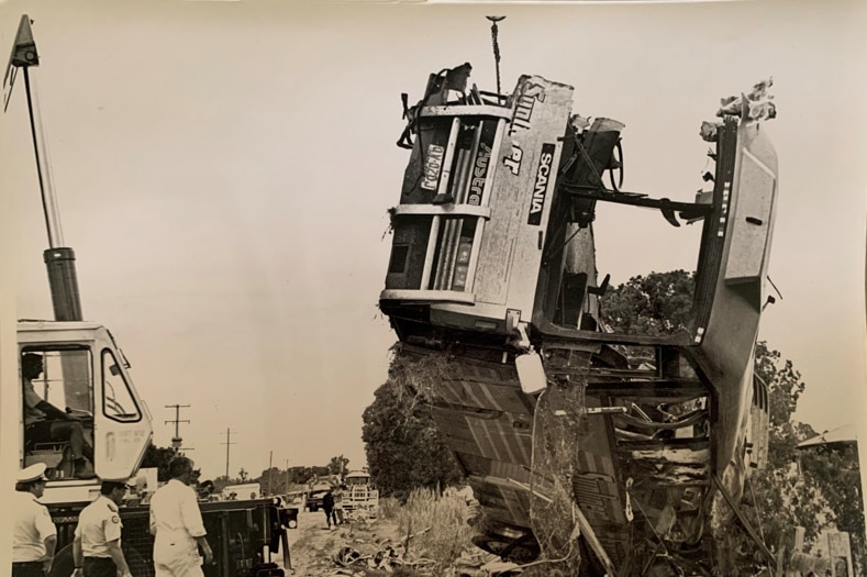 A crane lifts the wreck of a crashed bus.