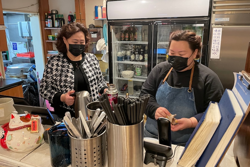 Two women prepare food in a commercial kitchen