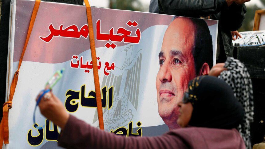 A woman points a banner for the Egyptian president