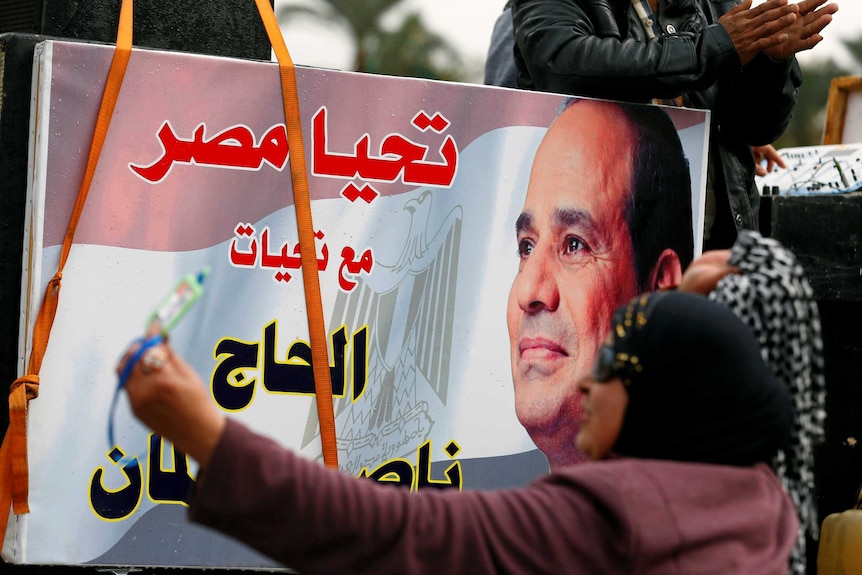 A woman points a banner for the Egyptian president