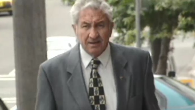 An older man in a grey suit walks up the street