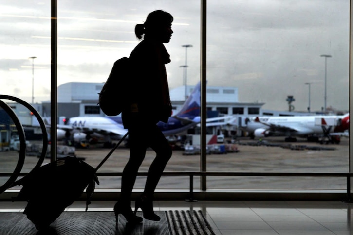 A student dragging her suitcase at the airport.