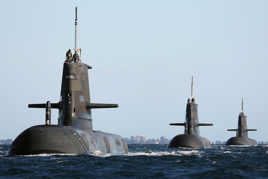 A fleet of three submarines prowling in train along a bitter-looking sea.