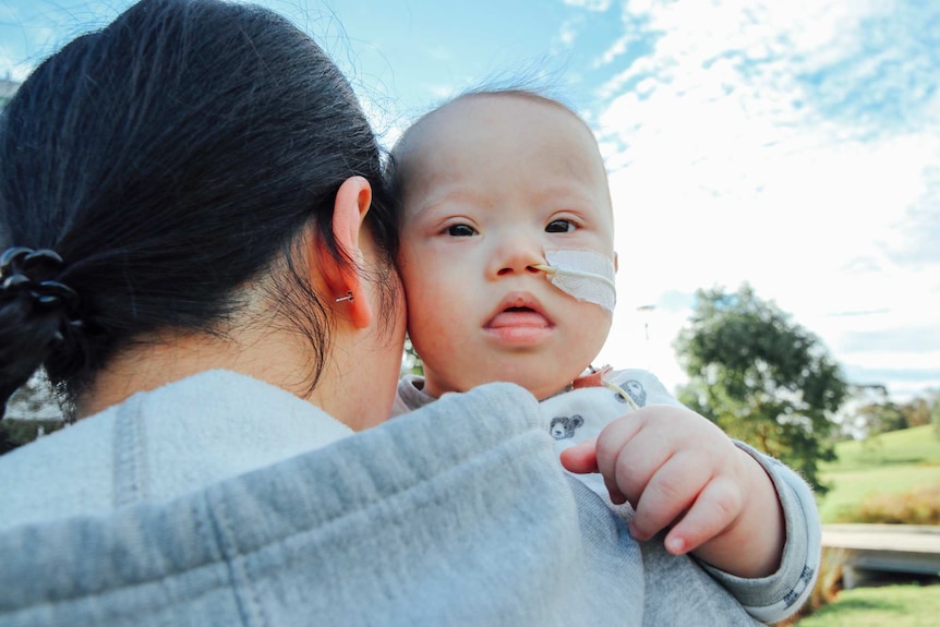 The back of Sarah Yang's head with baby Leo on her shoulder.