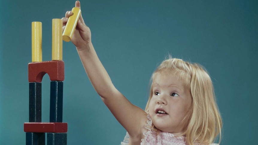 girl playing with toy blocks stacking them high