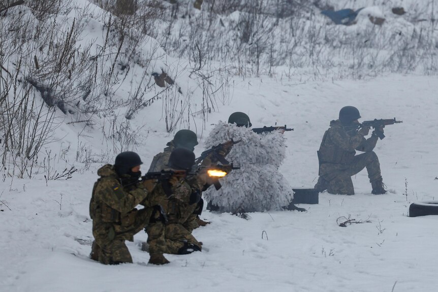 Five soldiers fire guns at an unknown target surrounded by white snow