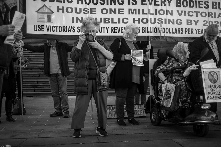 Louise Goode holding a camera at a rally atMelbourne's Parliament House.