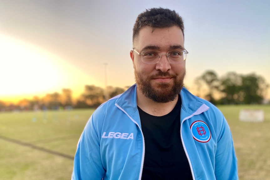 Man with glasses smiles on soccer field
