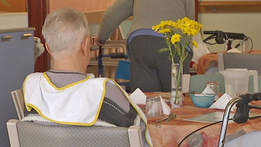 Anonymous elderly man sitting at a table in a nursing home.