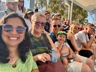 An older woman with short hair sits between a young family.